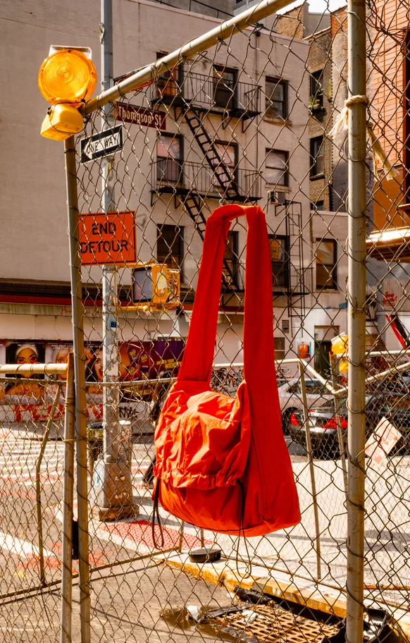The orange tote hung on a chain-link fence
