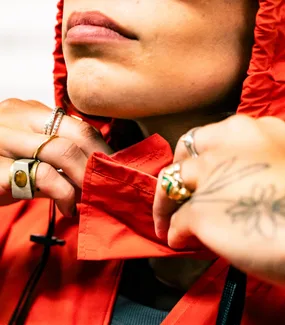 Hands gripping the collar of the orange LIFELINE tote worn as a hood
