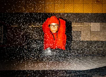 Standing on a subway platform wearing the orange tote as a hood